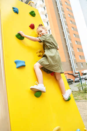 Kid at playground. Pretty face. Cute school child. Active vacation. Small people. Summer freedom. Happy children concept. Lifestyle action. Climbingの写真素材