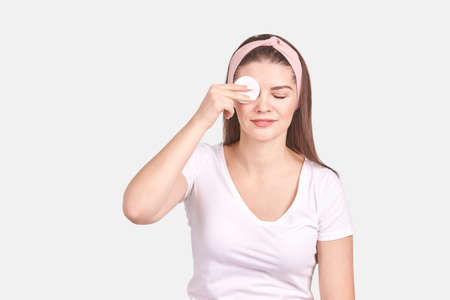 Pretty young woman gesture. Studio portrait. Female person. Isolated background. Morning bathroom routine. round cotton pad. Facial clean concept. Remove makeup lotionの写真素材