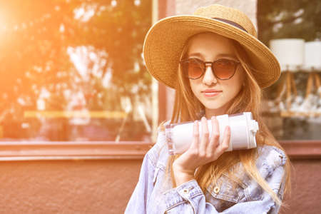 Pretty girl drink beverage outdoors. Buy takeaway coffee in own cup. Caucasian real people. Single female person. Staycation ecology concept. Positive attractive human. Jeans. Sustainable lifestyleの写真素材