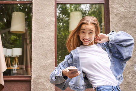 Pretty girl outdoors. Caucasian real people using mobile phone. Single female person. Staycation ecology concept. Positive attractive human portrait. Funny emotionsの写真素材
