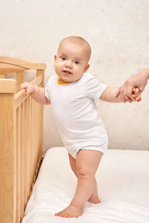 Cute small boy standing at house. Childhood concept. Light background. Smiling child. Happy emotion. Copyspace. Stay home. Onesie mockup. White clothesの写真素材