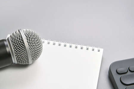 Podcast concept. Black microphone, content notebook. Close up. Audio music device. Recording production. School knowledge equipment. Home online teaching. Grey backgroundの写真素材