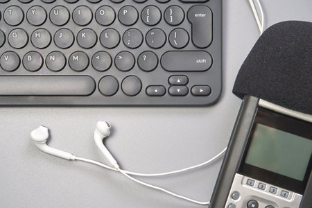 Podcast concept. Black microphone recorder, content notebook keypad with white earphones. Close up. Audio music device. Recording production. School knowledge equipment. Home online teaching. Greyの写真素材