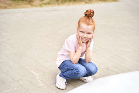 Little girl outdoor portrait. Red hair. Happy baby face. Female person at backyard. American smart schoolgirl. Positive child expression. Smile kid face. Summer timeの写真素材