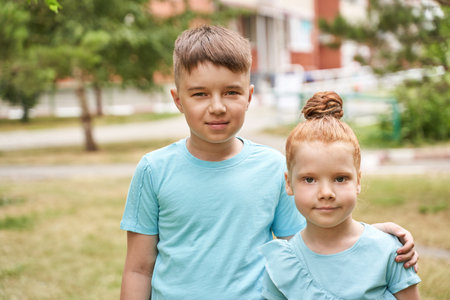 Little girl and boy at backyard. Green casual dress. Family outdoor portrait. Female and male children. Summer day. Happy sibling faces. Friendship concept.の写真素材