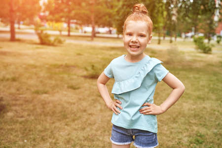 Little girl outdoor portrait. Red hair. Happy baby face. Female person at backyard. American smart schoolgirl. Positive child expression. Smile kid face. Summer timeの写真素材