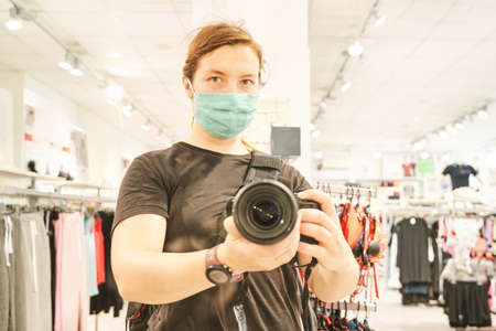 Camera self portrait. Big camera mirror photo at shop. Blur mall background. Green ecology mask. Zero waste people. Sad emotionの写真素材