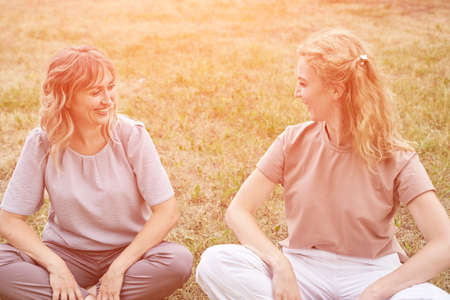 Pretty young women chating at park. Two happy female persons outdoors. Summer business portrait. Lady talking to friends. Blonde hair. Cute adult students at townの写真素材