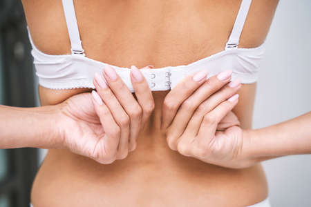 Young woman showing manucure hands. Closeup view. Female underware. Undress bra self. Remove lady back clothesの写真素材