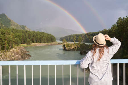 Travel woman in hat. Mountain trekking. Hipster journey. Unrecognizeble people. Nature landscape with river. Siberia view. Tourist person. Staycationの写真素材