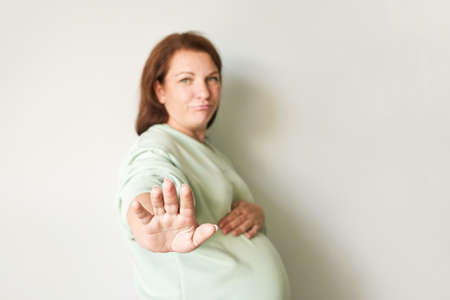 Pregnant woman forbidden sign. Medical hospital. Health care check. Female patient. Pandemic concept. Stop gesture. Serious face. Selective focusの写真素材