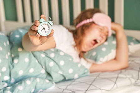 Morning routine. Young pretty woman wake up at home. Bed time. Snooze alarm. Lazy lifestyle female portrait. Bedroom apartment. Early time. Asleep conceptの写真素材