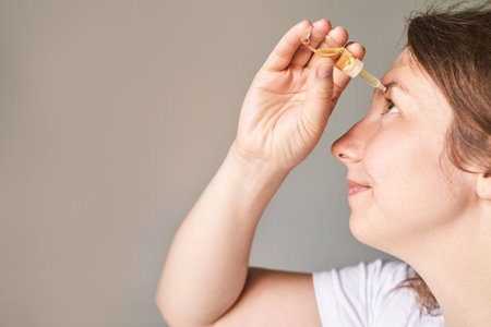 Young woman doing morning routine. Home maternity treatment. Health care concept. Female person. Eyedrop glaucoma concept. Eyewash treatment. Yellow dropの写真素材