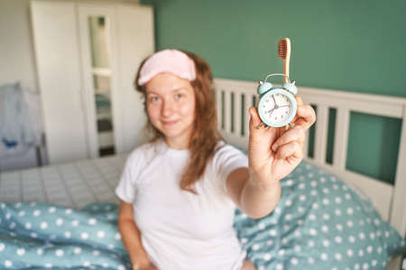 Morning routine. Young pretty woman wake up at home. Bed time. Snooze alarm. Lazy lifestyle female portrait. Bedroom apartment. Early time. Asleep conceptの写真素材