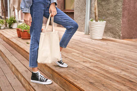 Girl with sustainable bug. Ecology lifestyle concept. Reusable flax shopper. Female person holding textile handbag. Outdoors market. Cotton eco totebag. Environmental choicesの写真素材