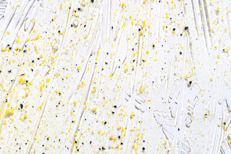 Face scrub texture. Cream skincare cosmetic. Organic stroke. Feet oily cleanser smudge. Particles in gel. White background. Top view. Yellow and black fluid treatmentの写真素材