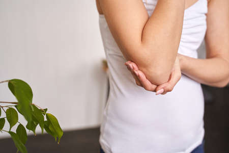 Young woman at office. Tired elbow. Female stress lifestyle. New normal education. Sad emotion. Ache concept. Pretty person. Exhausted worker painの写真素材