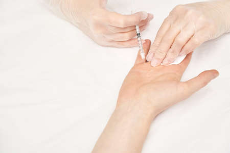 Palm injection at spa salon. Doctor hands in gloves. Closeup. Pretty male patient. Beauty treatment. Healthy skin procedure. Young woman face. Plasmolifting rejuvenationの写真素材