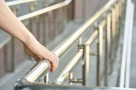 Hand using handrail for wheelchair. Man support. Steel construction. Mall escalator safety guard. Disabled rampの写真素材