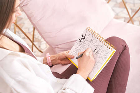 Young woman drawing neurographics indoors. Psychology treatment. Home vacation portrait. Alone in...