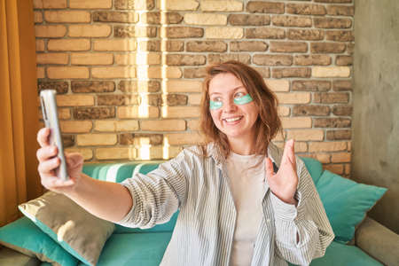 Young woman doing self portrait indoors. Home vacation portrait. Blogger selfie video. Alone in...