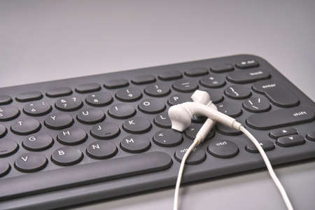 Podcast concept. Black microphone recorder, content notebook keypad with white earphones. Close up. Audio music device. Recording production. School knowledge equipment. Home online teaching. Greyの写真素材