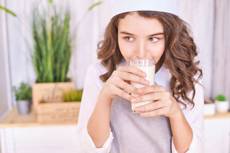 Young girl cooking at kitchen with vegetables. pretty child portrait. Chef student. Attractive brunette. Children emotion. People baking in cook apron. Close recipe menuの写真素材