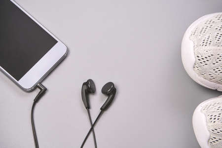 Listen podcast at running training. Black earphones heart shape. Grey background. Storylines jogging. Sport lifestyle concept. Gym sneakers audio playlistの写真素材