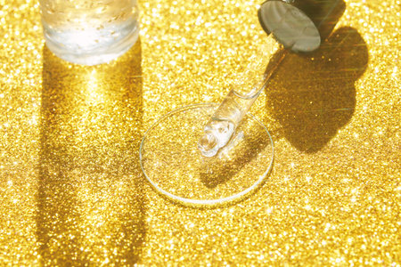 Serum gel texture swatch. Transparent drop with sparkles. Yellow bokeh background. Face skincare product. Liquid oil essence. Beauty collagen splash. Organic peeling treatment. Body health careの写真素材