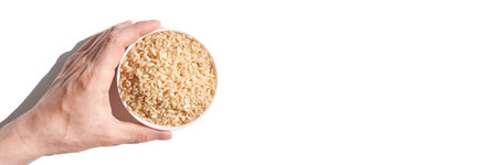 A bowl of uncooked brown rice, isolated against a white background. Healthy, savory dish includes whole grains like jasmine and basmati, showcasing a dieting Asian cuisine. Horizontal bannerの写真素材