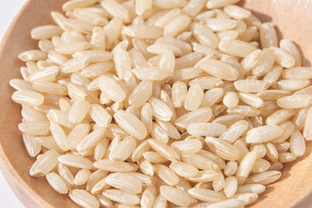 A closeup of long, uncooked brown rice grains on a wooden spoon surface, emphasizing the healthy, natural aspect of this whole food. Pile gluten textureの写真素材