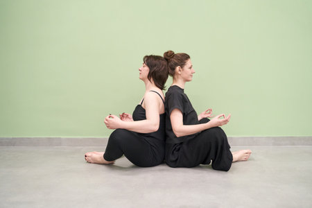 Yoga calm pose. Two person. Zen hand mudra. Lotus asana at studio training. Woman seating at floor....