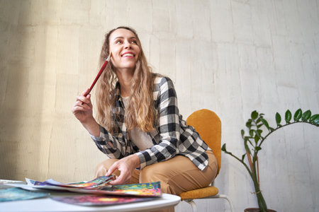Woman holding paint brush at hand. Watercolor color palette. Art drawing process. Professional education graphic study. Painting hobby class studio. Workshop equipment. Happy businesswomanの写真素材