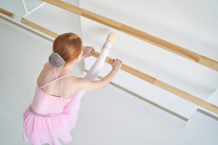 Young ballet girl at studio lesson. Training performance. Stretching exercise pose. Ballerina practice balance technique. Classical elegance fitness. Dancing costume, twine. Pink dress, skirtの写真素材