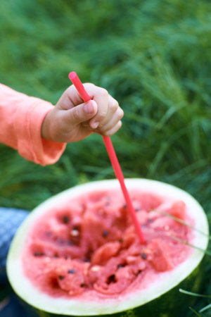 Child enjoying a refreshing watermelon drink in summer garden setting. Weekend family cheerful playの写真素材