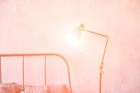 Minimalist bedroom with soft lighting and stylish bedside lamp against warm textured wallの写真素材