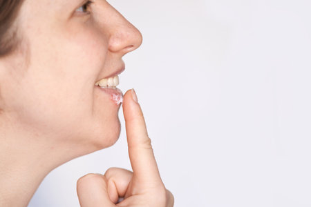 Woman applying lip balm on chapped lips for skincare and hydration routine. Profile view