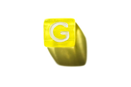 Yellow block with letter g casting shadow on white background: alphabet and learning concept