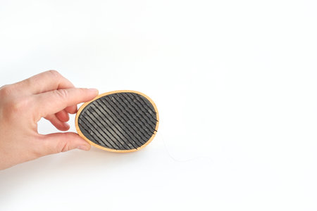 Hand holding charcoal air purifier filter against white background for clean fresh air
