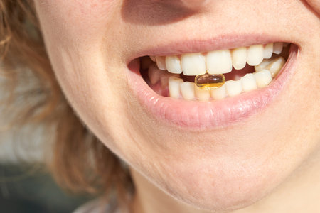 Close-up of womans smile with vitamin capsule between teeth highlighting nutritional health and wellness conceptの写真素材