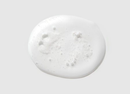 Close-up of white liquid soap with bubbles on gray background reflecting cleanliness and minimalist beauty conceptsの写真素材