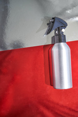 Modern aluminum spray bottle on red and silver surface with minimalist style for home and beauty applications.の写真素材