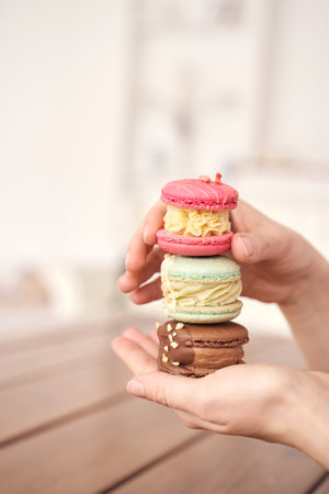 Colorful stack of macarons in hand against soft background with detailed focus on delightful...
