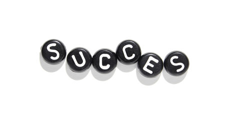 Creative spelling of success with black and white lettered beads on white background