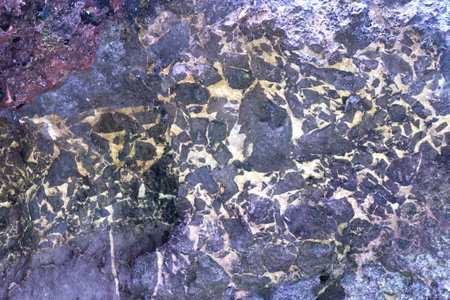 Abstract geometric pattern on rock surface with natural texture and color variations.