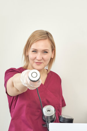 Female caucasian young healthcare worker holding medical device in professional setting.