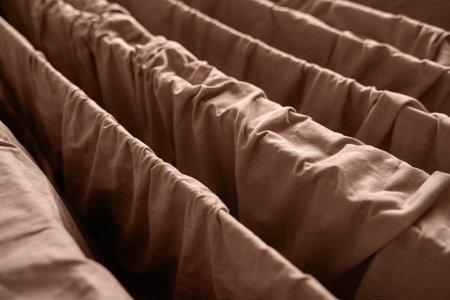 Close up of brown fabric with gathered texture and parallel folds creating a cozy and warm textile pattern.の写真素材