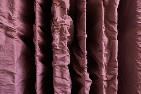 Close up of crumpled burgundy fabric drapes showcasing textured folds and rich color.の写真素材