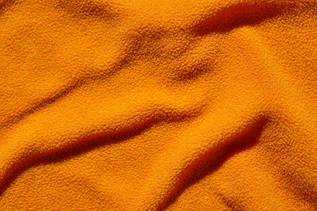 Soft orange fabric texture with dynamic folds and shadow play creating a cozy and warm aesthetic.の写真素材