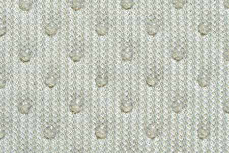 Textured beige fabric with raised dotted pattern close up.